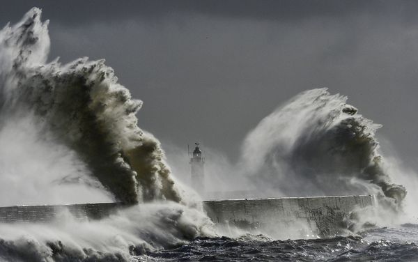 Waves hit a lighthouse in Newhaven, England, on February 15, amid record levels of flooding. More intense storms are an example of extreme weather brought on by climate change, experts say